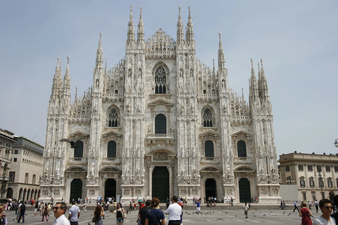 The facade of Milan Cathedral seen head-on from the piazza, with its forest of spires and the Madonnina on top