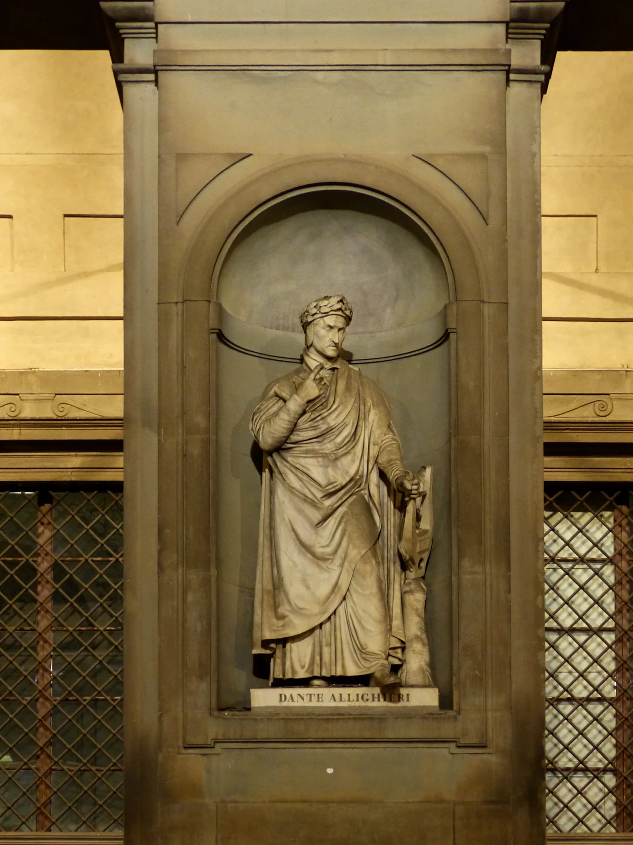 The statue of Dante Alighieri in a niche of the Uffizi loggia at night