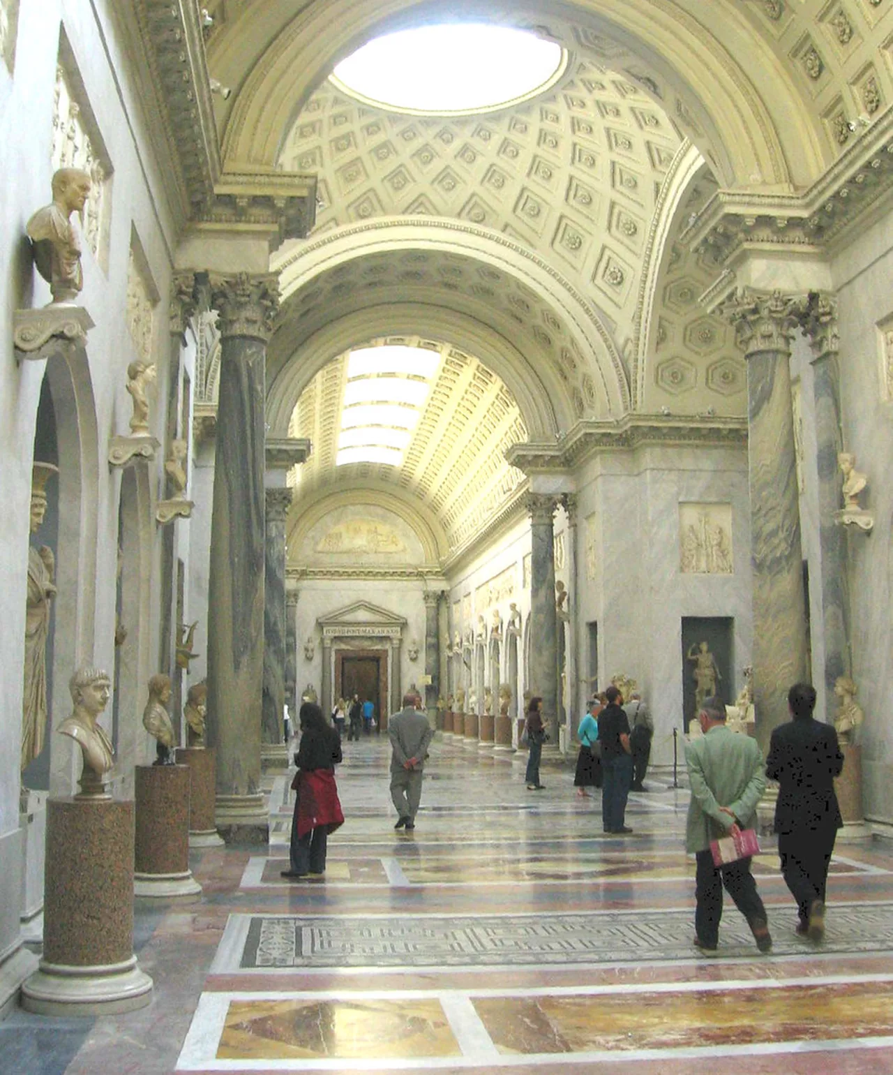 Visitors walk through a statue gallery inside the Vatican Museums
